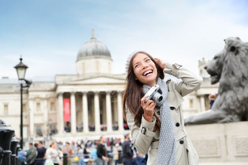 Girl holding a camera smiling in London-Best cities in Uk to Visit 